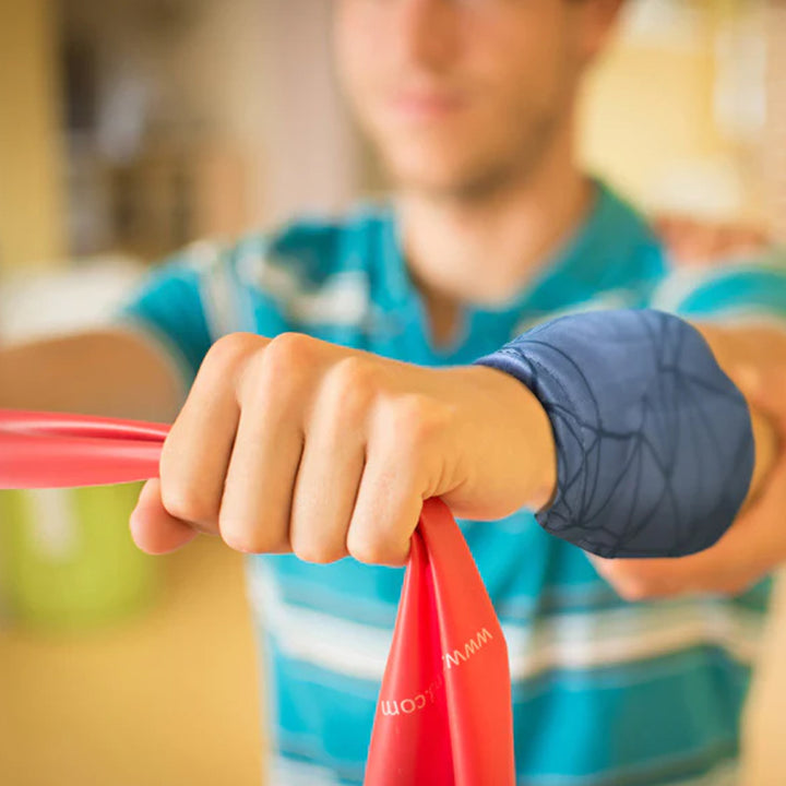A man in athletic wear is completing forearm exercises while wearing a grey HurtSkurt wearable ice pack for forearm pain relief.