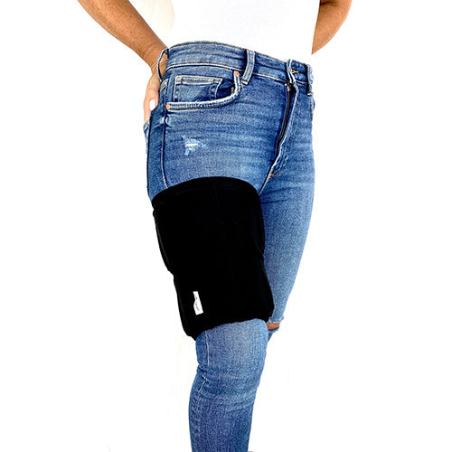 A man wearing a solid black extra large ice pack around his thigh for pain relief.