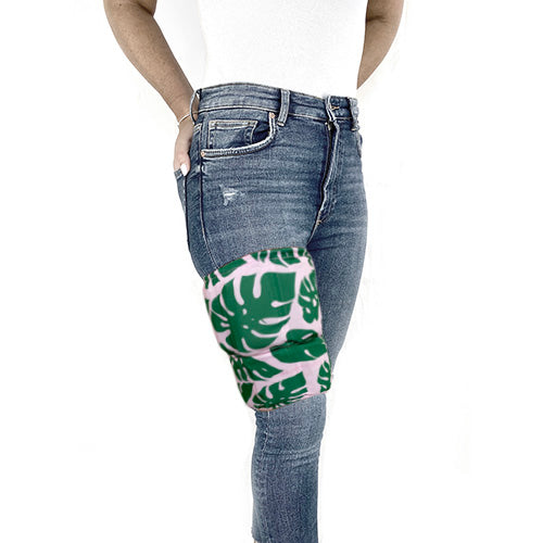 A man wearing a tropical patterned green and pink extra large ice pack around his thigh for pain relief.