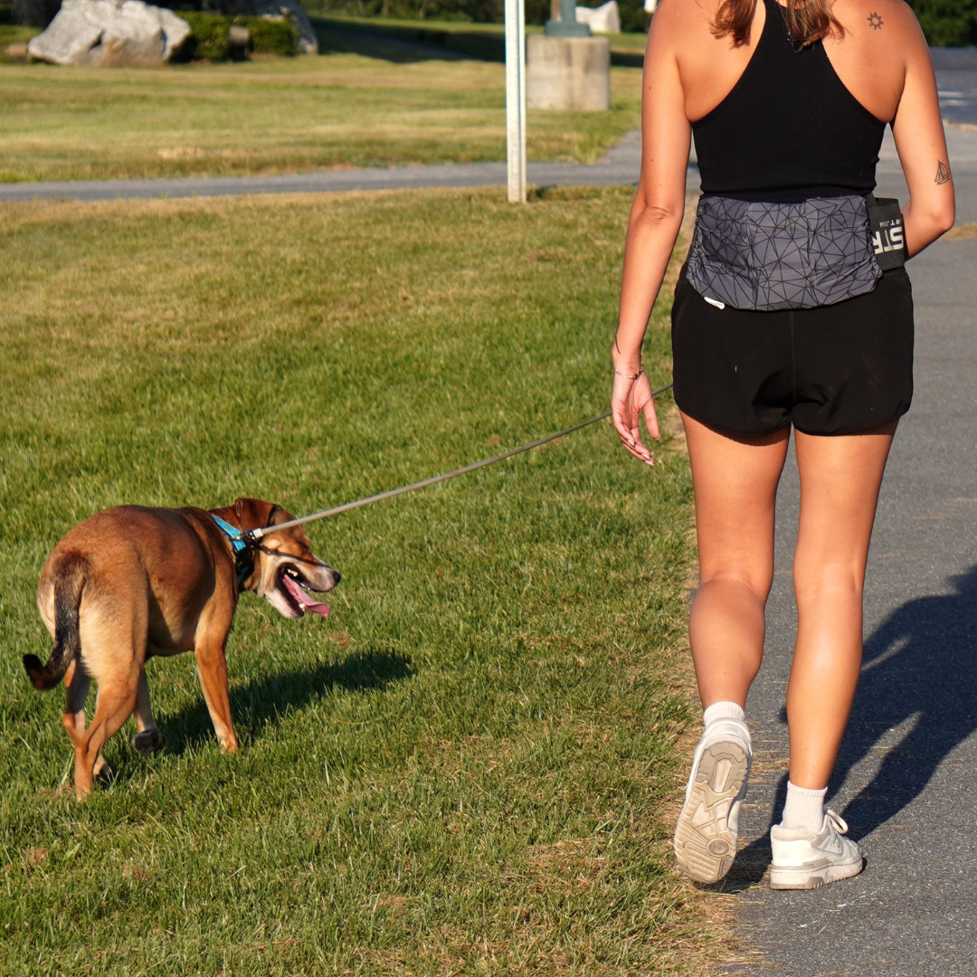Woman walking her dog while wearing a large HurtSkurt on her lower back using a SkurtStrap to hold it in place