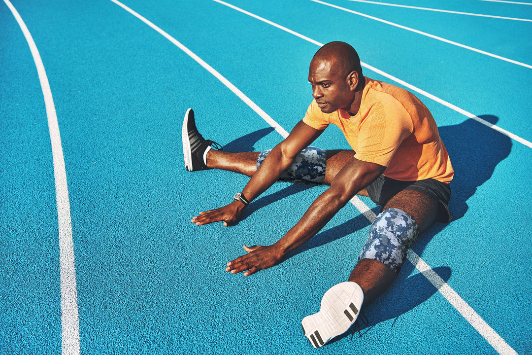 Track athlete wearing a medium HurtSkurt on his knee as he stretches before a race