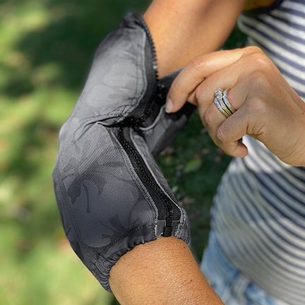 Woman wearing a ZipSkurt ice pack sleeve in a black floral print on her elbow